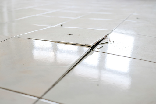 Loose cracked floor tiles lifting from the surface.